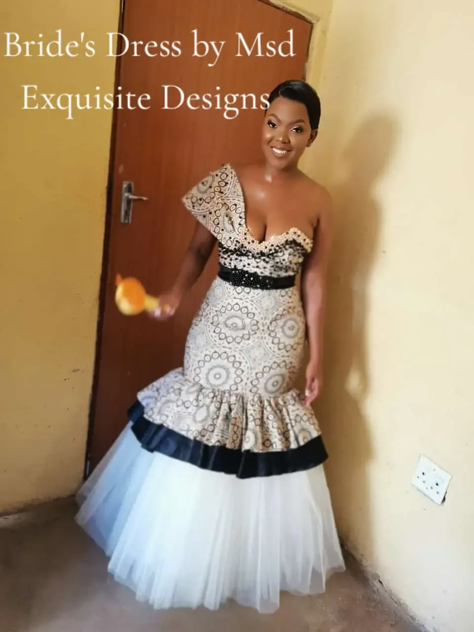 Bride wearing a cream and black shweshwe mermaid wedding gown with pearl beading and a tulle tiered hem