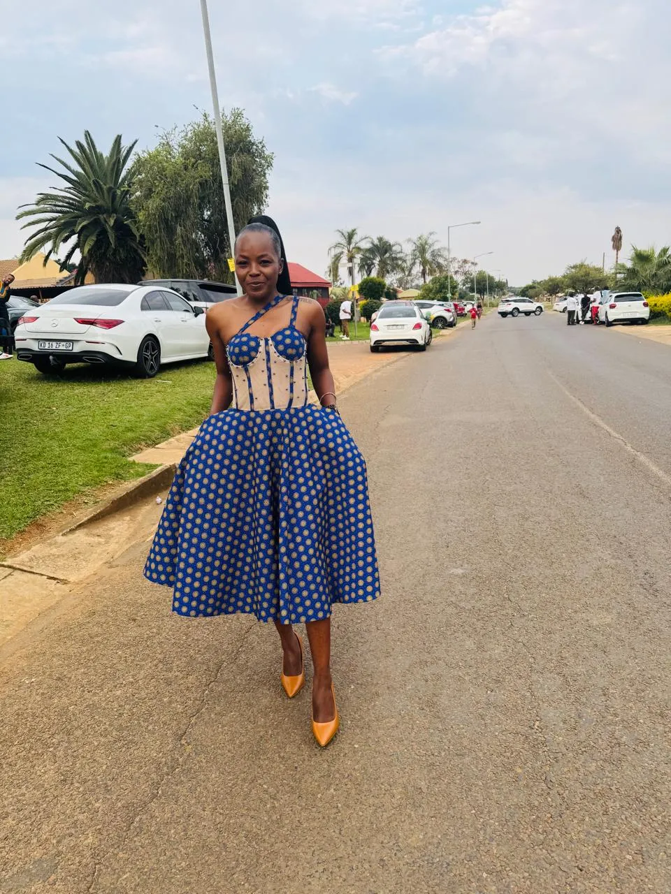 Woman wearing a custom cobalt shweshwe midi dress with a sheer boned corset bodice and full circle skirt