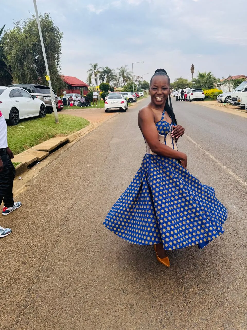 Woman twirling in a custom cobalt shweshwe circle skirt showing the full sweep of the pleated hem