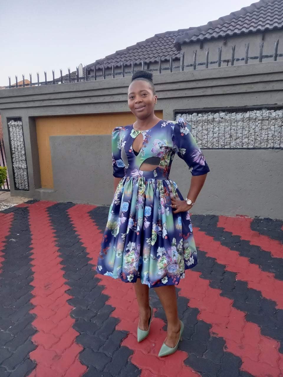 Woman wearing a floral printed satin dress with keyhole neckline, waist cut-outs and a full box-pleated skirt