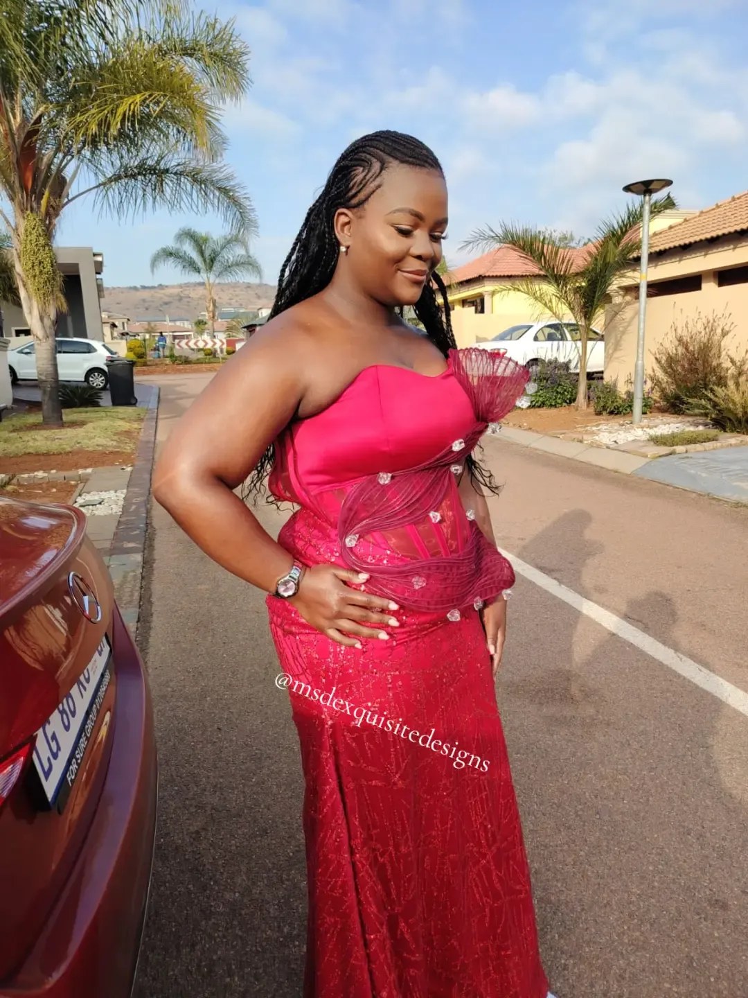 Woman wearing a custom crimson evening gown with sheer boned corset waist, organza swirls and crystal embellishments